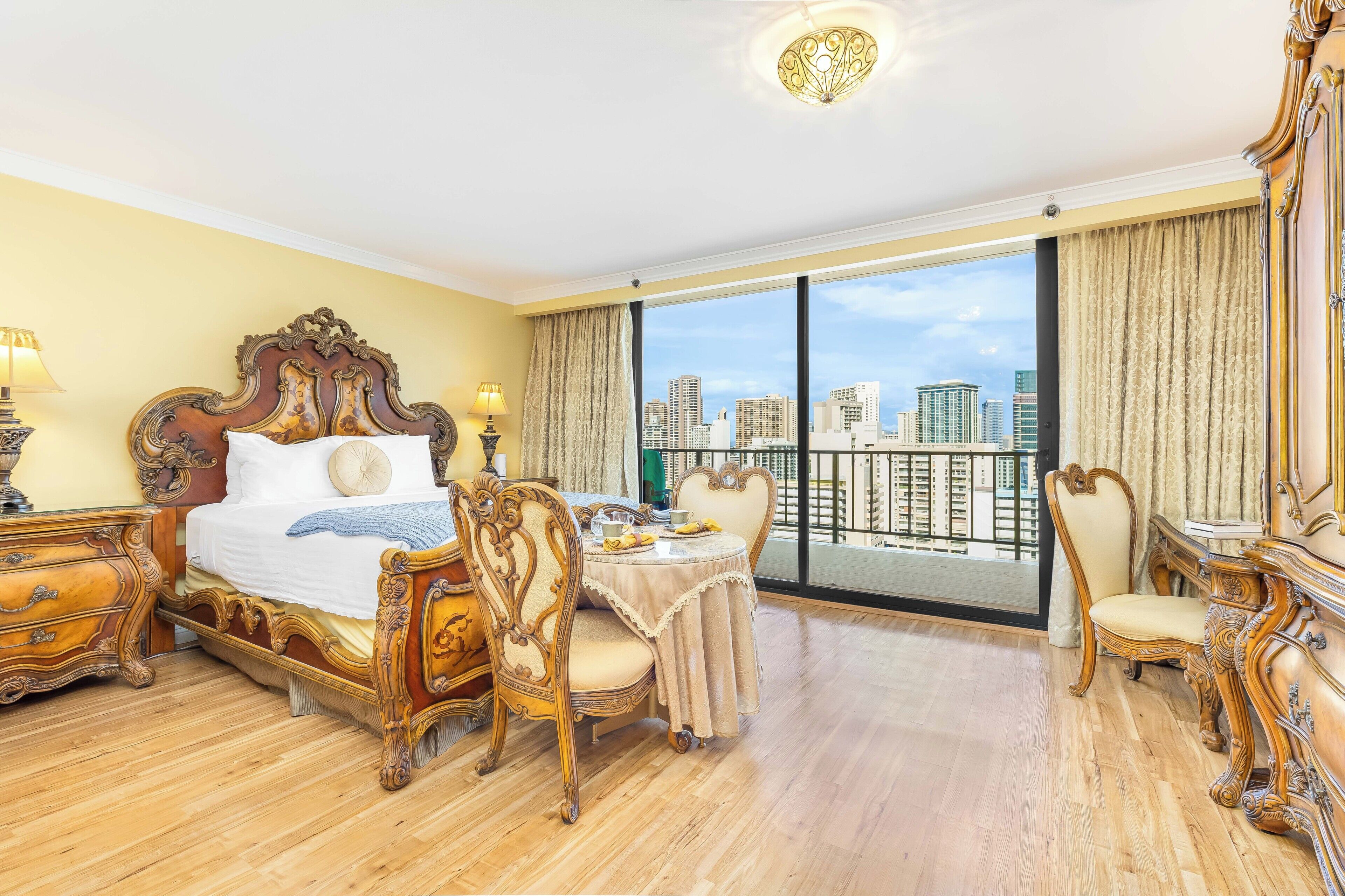 Ein geräumiges Hotelzimmer mit einem großen Bett, einer Essecke und einem Balkon mit Blick auf die Stadt.