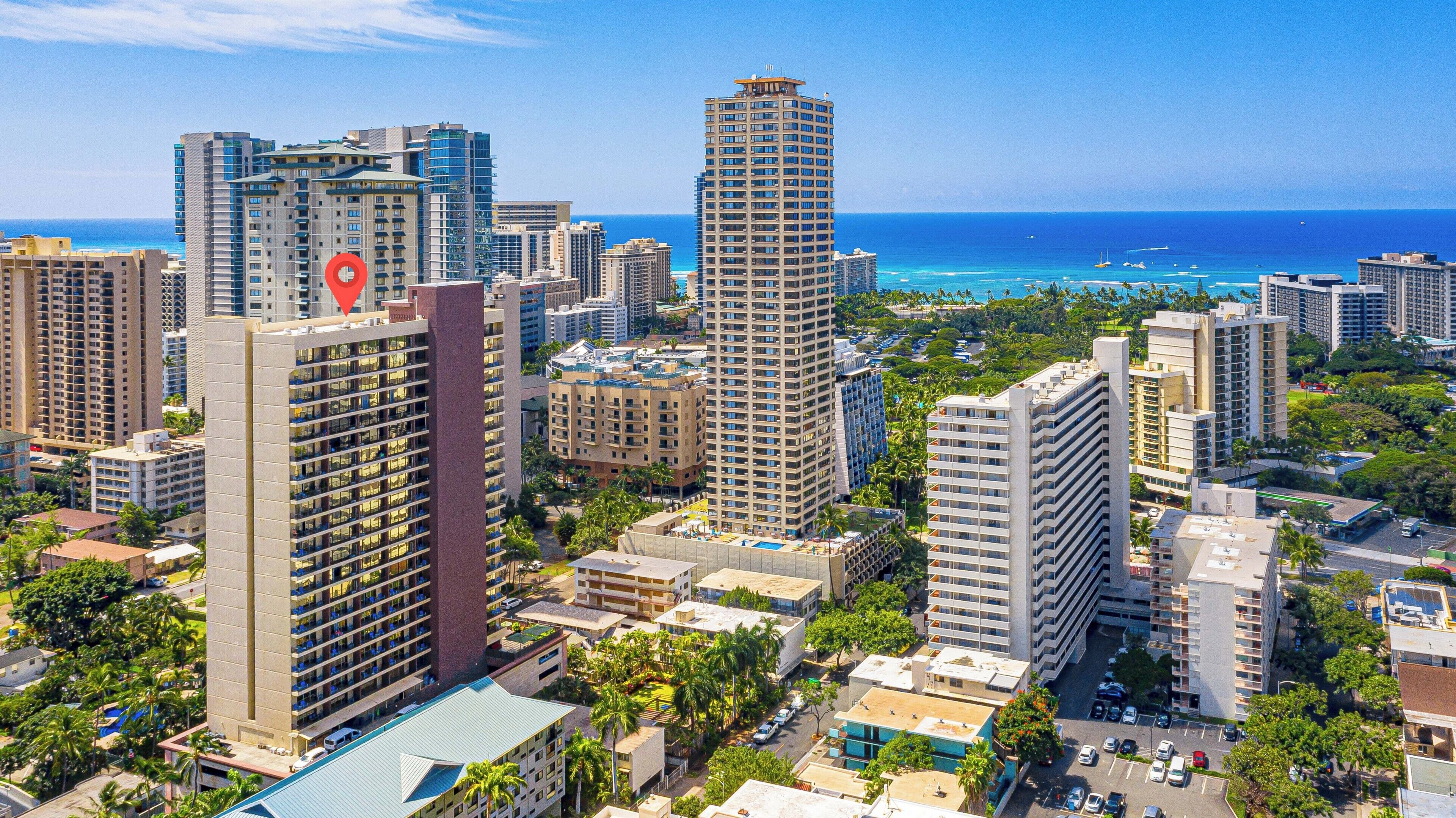 A high-rise hotel with multiple floors, a rooftop pool, and a view of the ocean.