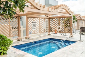 Ein Schwimmbecken mit einer Holz-Pergola, Sicherheitsschildern und einem Rettungsring.