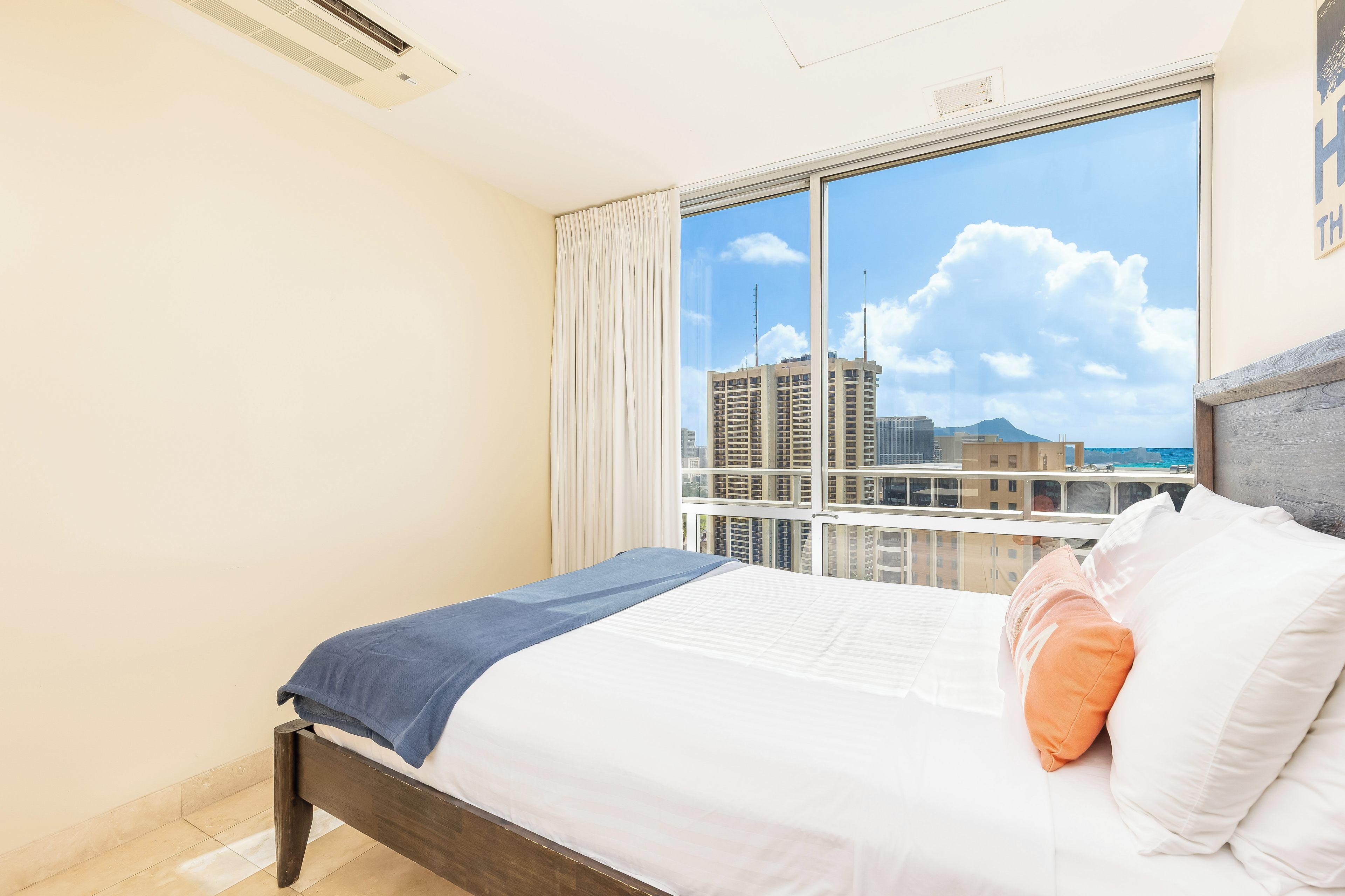 Habitación de hotel con un amplio ventanal que ofrece vistas a la ciudad, una cama impecable y un diseño moderno.