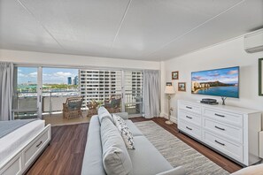 Ein geräumiger Balkon mit Blick auf die Stadt, ein bequemes Sofa, ein Fernseher und eine Essecke mit Stühlen.