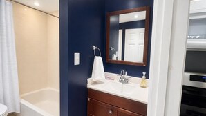 Un bagno con una vasca, un lavandino con specchio e un water.