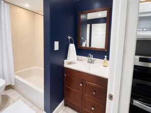 Un baño con bañera, lavamanos con espejo y retrete.