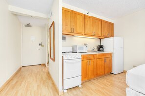 Eine kleine Küche mit Holzausstattung, einem Herd, einer Mikrowelle und einem Kühlschrank.