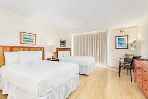 Ein Hotelzimmer mit zwei Betten, einem Schreibtisch, einem Stuhl und einem fensterbepflanzten Fenster.