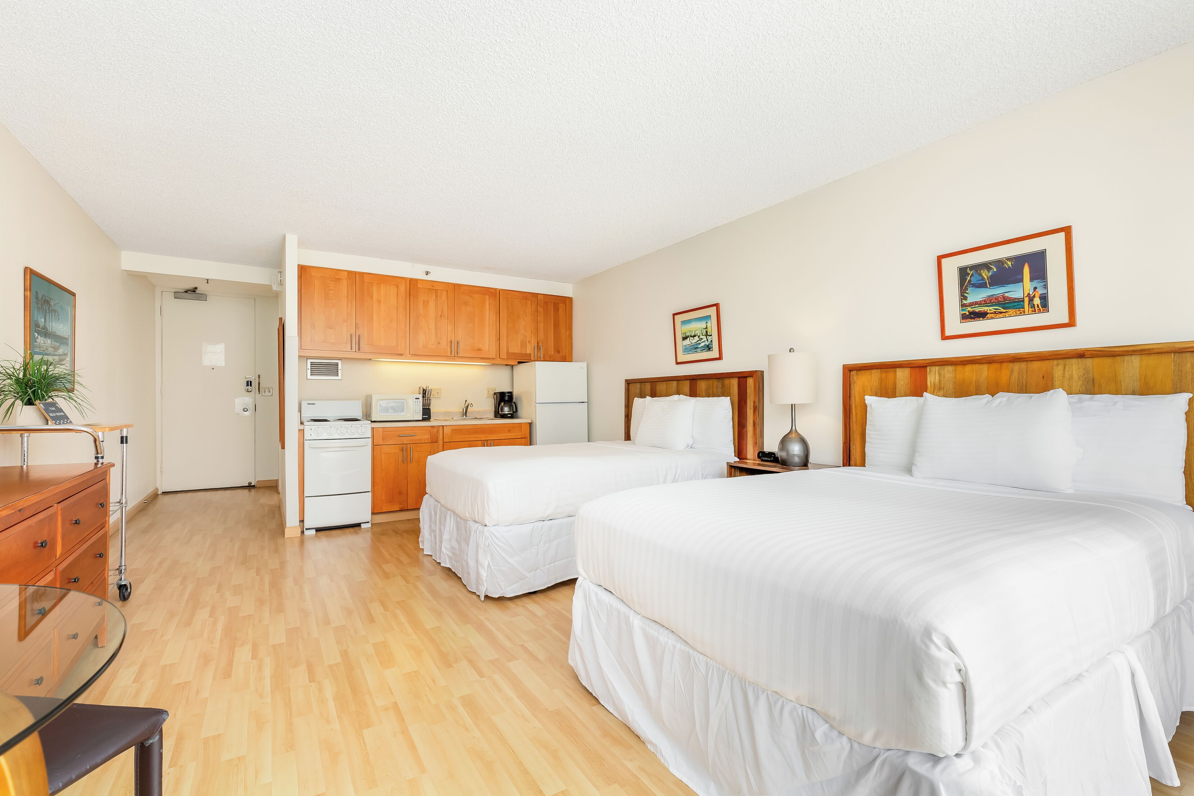 Una habitación de hotel con dos camas, kitchenette y baño.