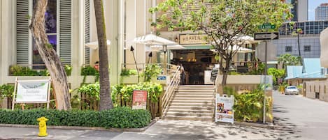 A hotel entrance with a staircase leading to the lobby, surrounded by greenery and palm trees.