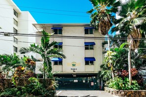 Ein Gebäude mit einem Schild, das „Cabanas Waikiki 2024“ zeigt, und einem verschlossenen Eingang, der von tropischen Pflanzen umgeben ist.