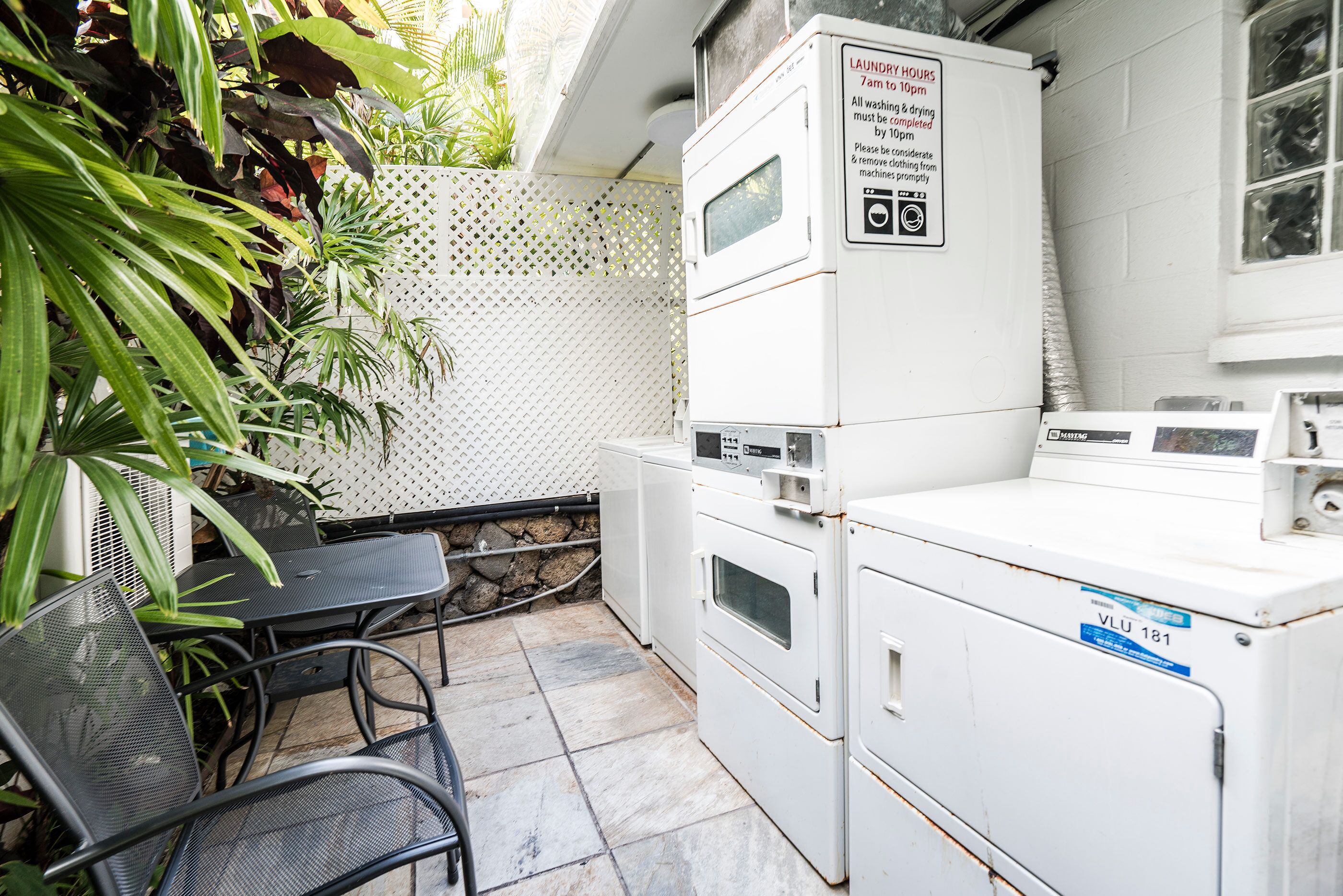 A laundry area with stacked washing machines and a table with chairs.