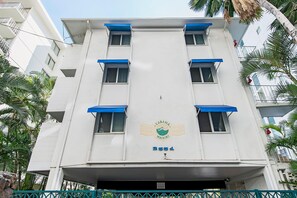 Un immeuble à plusieurs étages, doté d’une façade blanche et d’auvents bleus, sur lequel on peut voir un logo et le numéro 2551.