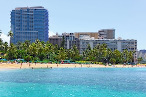 Ein Strandhotel mit mehreren Hochhäusern, Palmen und einem Sandstrand.