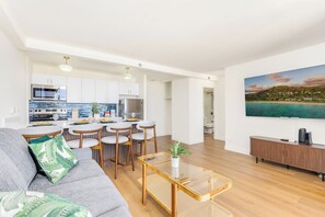 A modern living room with a sofa, coffee table, and a TV mounted on the wall. - Breathtaking Waikiki Sunset Ocean and Diamond Head View W/amazing Amenities (Honolulu)
