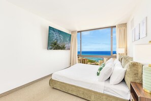 Ein Hotelzimmer mit einem großen Bett, Blick auf den Ozean und einem Gemälde an der Wand.