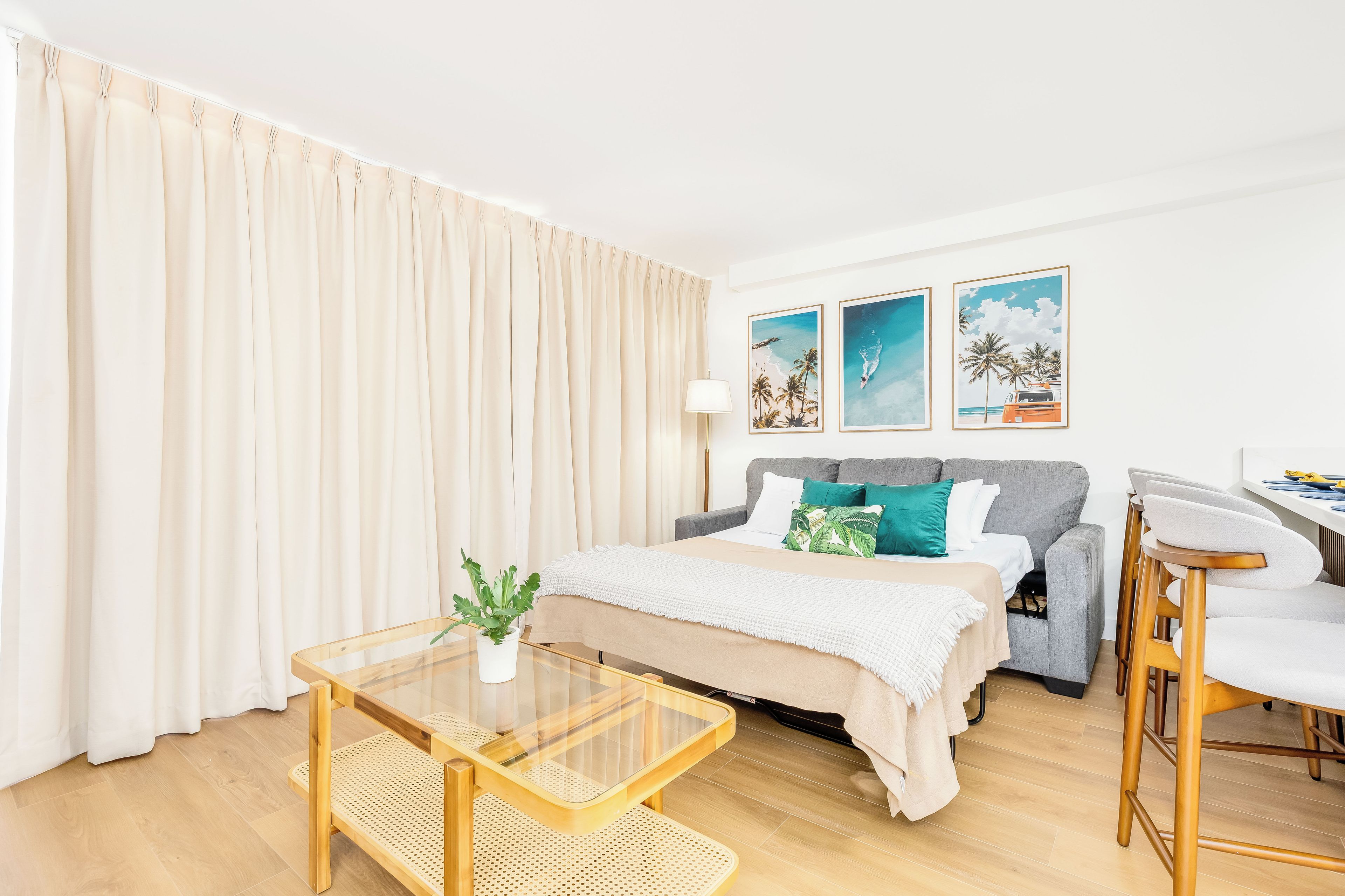 A modern hotel room with a bed, a dining area, and a large window with curtains.