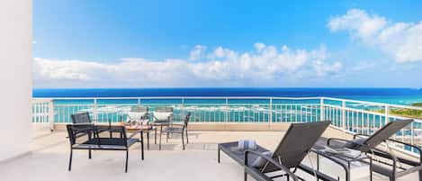 A balcony with outdoor furniture, a view of the ocean, and a railing.