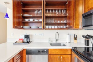 A kitchen with wooden cabinets, a microwave, a dishwasher, and a sink. - Ocean-marina Views PH at Ilikai Hotel by the Beach W/full Kitchen & Free Wifi (Honolulu)