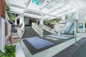 A modern hotel lobby with a central staircase, an elevator, and a glass ceiling. - Ocean-marina Views PH at Ilikai Hotel by the Beach W/full Kitchen & Free Wifi (Honolulu)