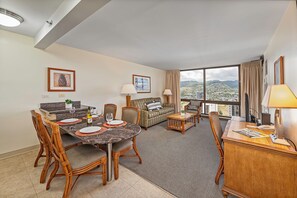 A hotel room with a dining area, a sofa, a desk, and a large window offering a city view. - MT & Golf Course Views Waikiki Sunset by the Beach W/full Kitchen & Wifi (Honolulu)