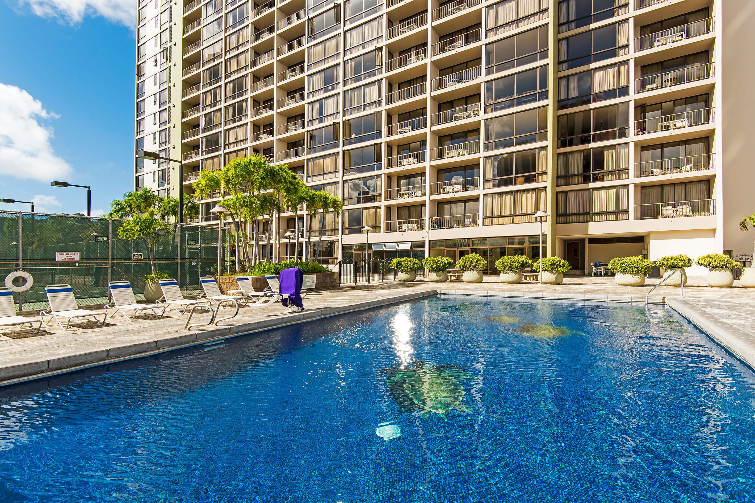 A hotel with a swimming pool, multiple balconies, and outdoor seating areas.