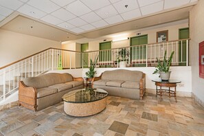 A spacious living area with two sofas, a glass coffee table, and a staircase with a railing. - MT & Golf Course Views Waikiki Sunset by the Beach W/full Kitchen & Wifi (Honolulu)