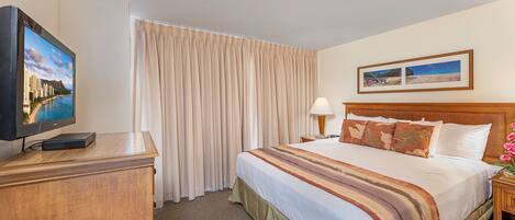 A hotel room with a bed, a television, a lamp, and a painting on the wall.