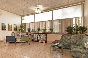 A reception area with a counter, seating, and a large window with blinds. - MT & Golf Course Views Waikiki Sunset by the Beach W/full Kitchen & Wifi (Honolulu)
