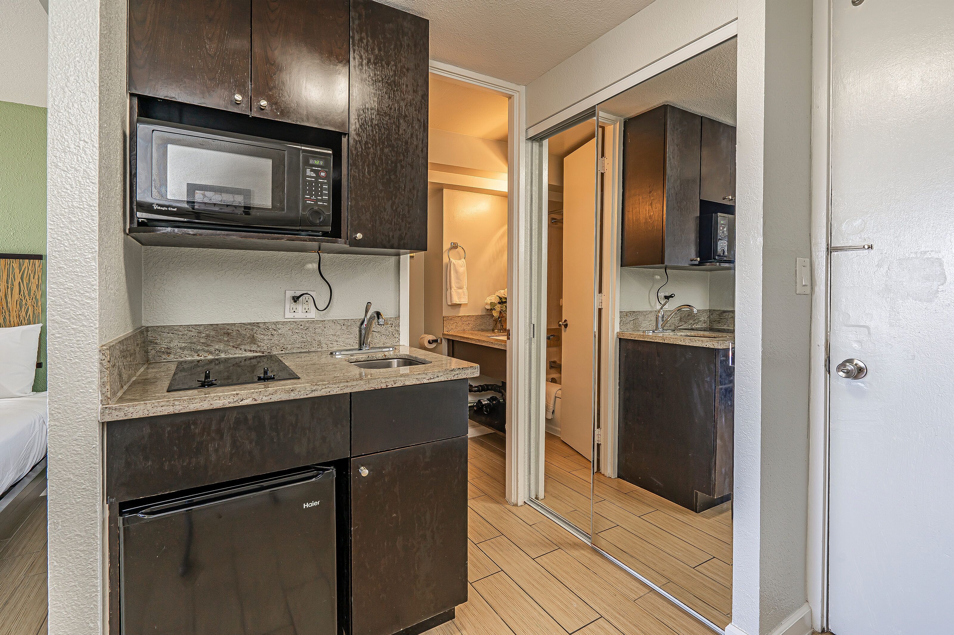 A compact kitchen with a microwave, sink, and dark cabinets.