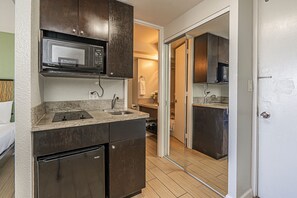 A compact kitchen with a microwave, sink, and dark cabinets. - Ocean-diamond Head Waikiki Condo at Island Colony Short Walk to the Beach (Honolulu)