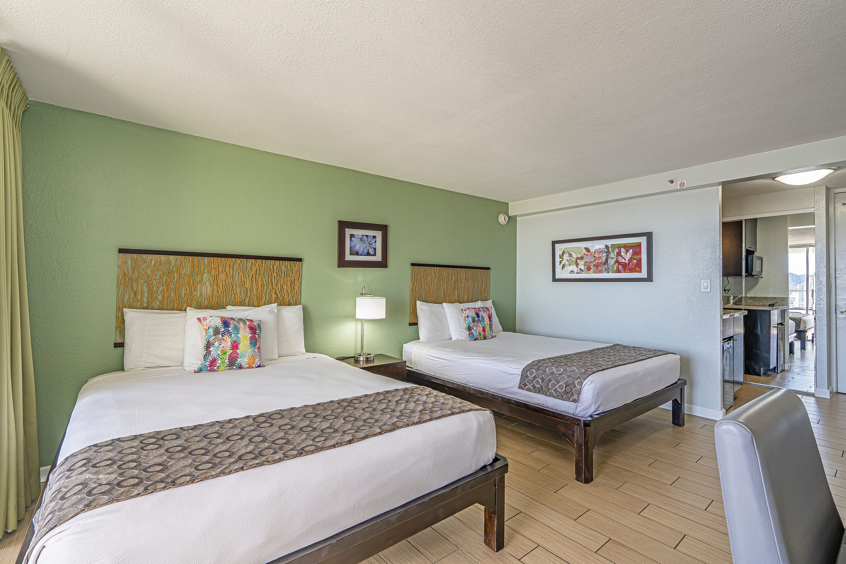 A hotel room with two beds, a desk, and a chair.