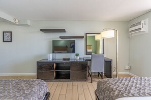 Une chambre d’h ôtel avec deux lits, un bureau doté d’un téléviseur à écran plat, un miroir et un appareil de climatisation.
