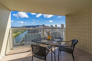 A balcony with a glass table and chairs, a bottle, and a book. - Ocean-diamond Head Waikiki Condo at Island Colony Short Walk to the Beach (Honolulu)