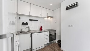 A modern kitchen with white cabinetry, a stainless steel sink, a red kettle, and a built-in oven. - Cosy 1Bdr Flat in Faro Downtown by LovelyStay (Faro)