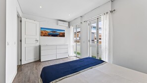 A bedroom with a bed, a wardrobe, a painting, and a sliding glass door to a balcony. - Cosy 1Bdr Flat in Faro Downtown by LovelyStay (Faro)