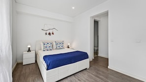 A bedroom with a white bed, a nightstand, a lamp, and a wall-mounted decoration. - Cosy 1Bdr Flat in Faro Downtown by LovelyStay (Faro)