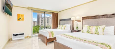 Habitación de hotel con dos camas, televisión, calefacción, ventana con vista a edificios y una lámpara.