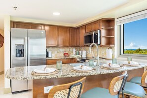 A modern kitchen with a central island, stainless steel appliances, and a view of the outdoors. - Luana at Waikiki 1-bed Ocean View Getaway in the Heart of Waikiki (Honolulu)