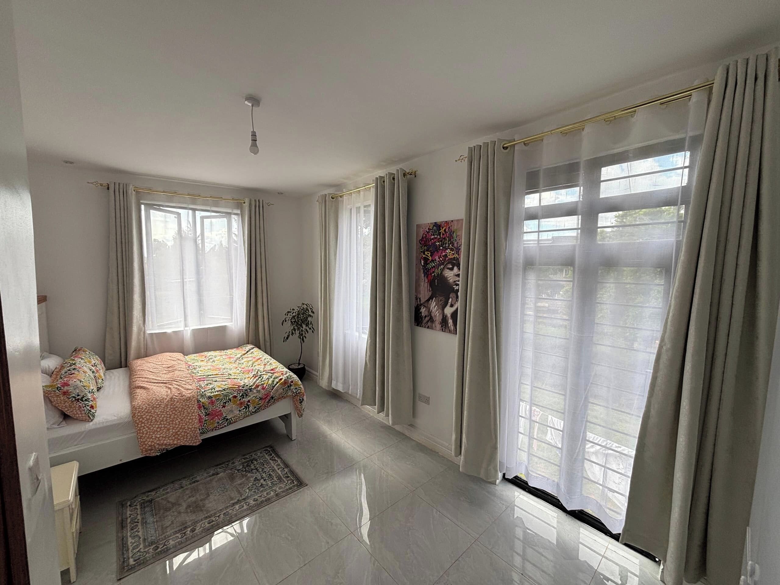 Una camera da letto con un letto, una finestra, un'opera d'arte appesa al muro e una luce a soffitto.