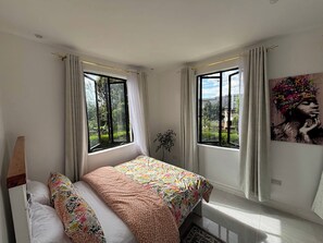 A bedroom with a bed, two windows, a plant, and a painting. - Prime Elgon View 5BR Family Home Private Secure in Eldoret (Eldoret)