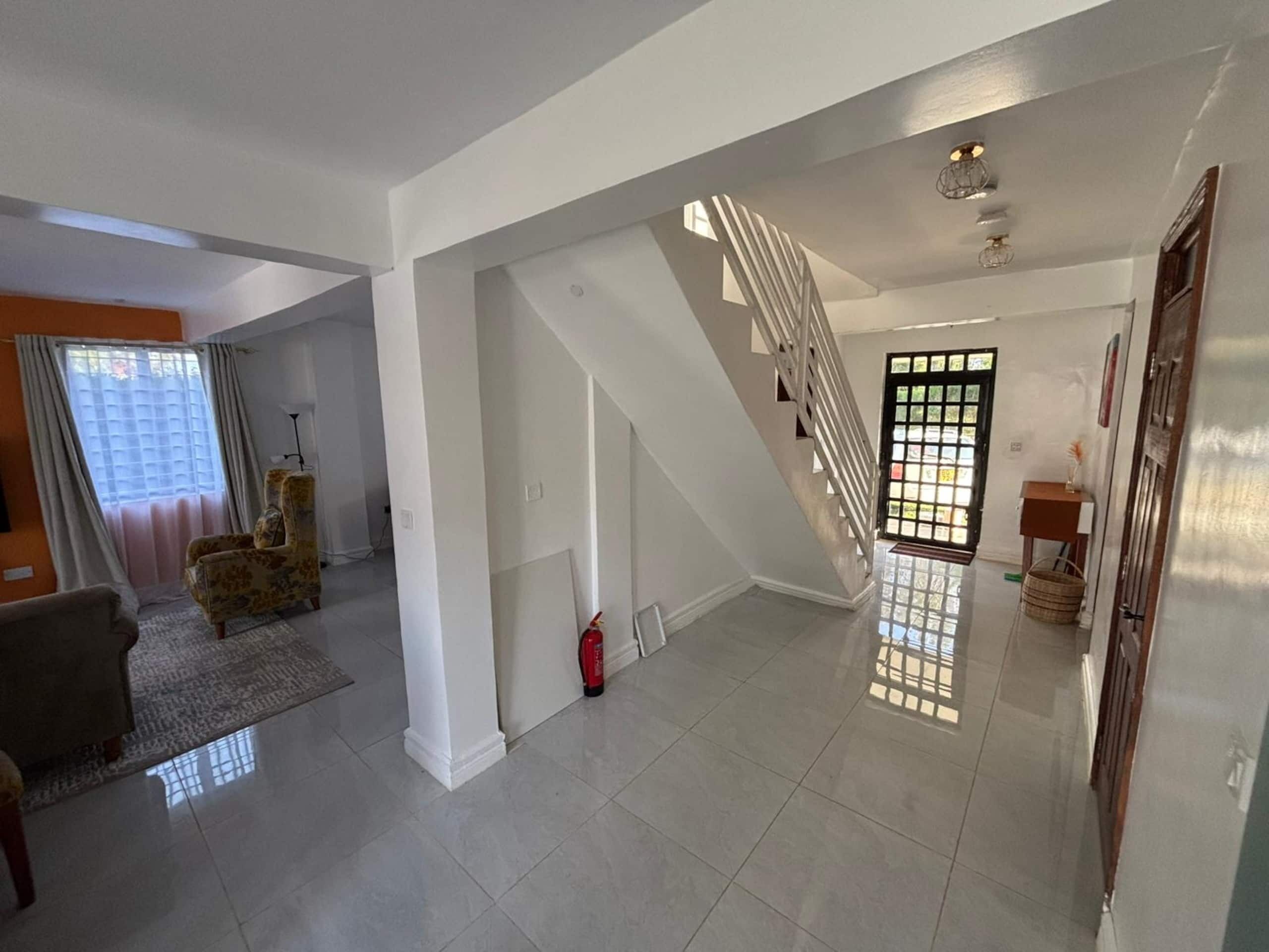A spacious living area with a staircase, a sofa, and a door leading to another room.