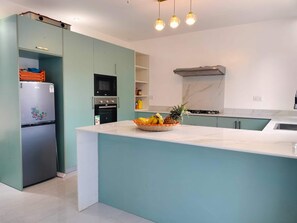 Una cocina moderna con una isla central, electrodomésticos integrados e iluminación colgante.