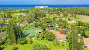 Zona residencial com quadra de tênis, casas e um grande hotel ao fundo.