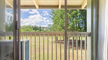 Ein Balkon mit Blick auf einen Rasen und Bäume, einer Holzpergola und einer großen Klimaanlage.