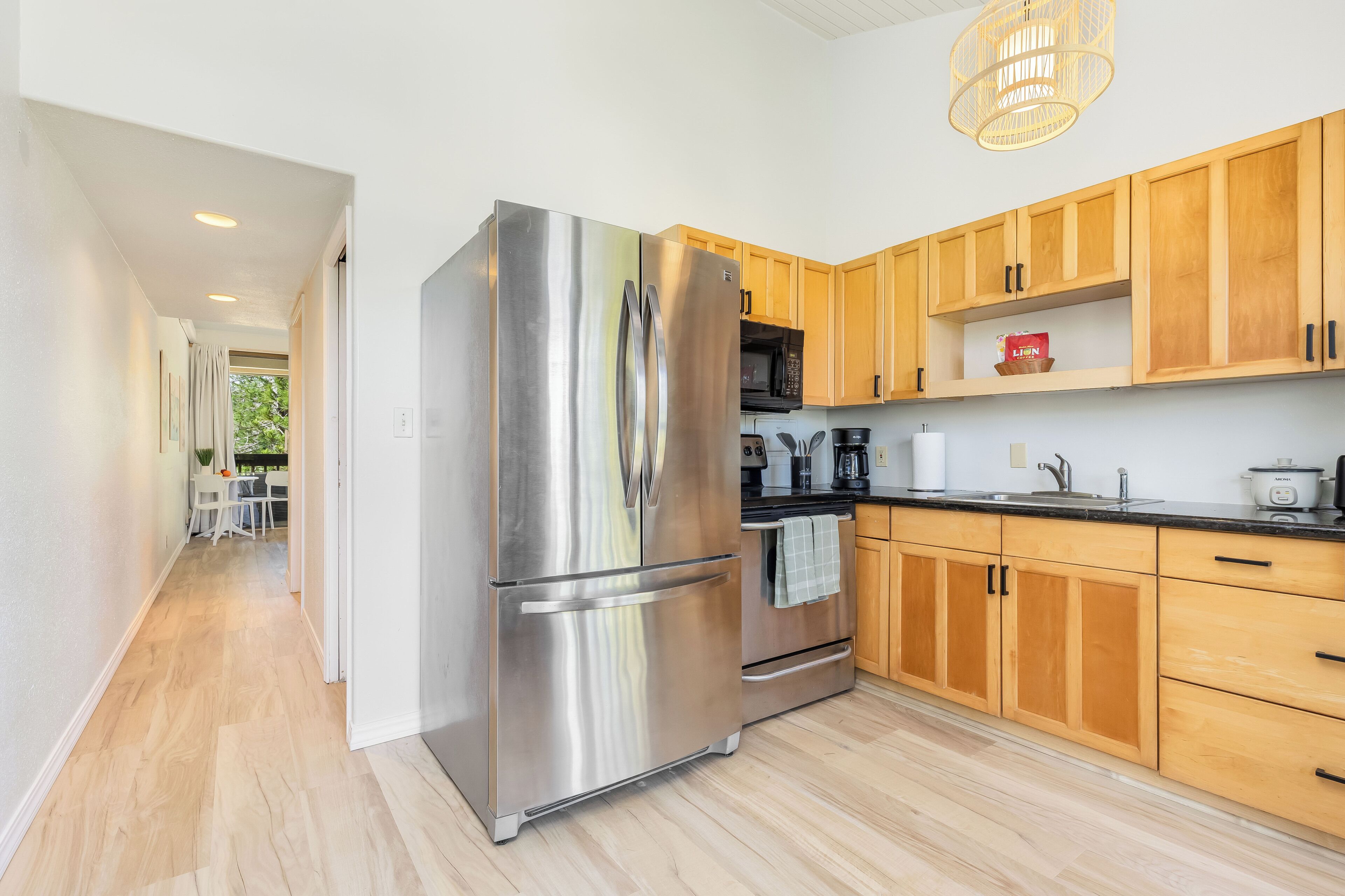A modern kitchen with stainless steel appliances, wooden cabinets, and a black countertop.
