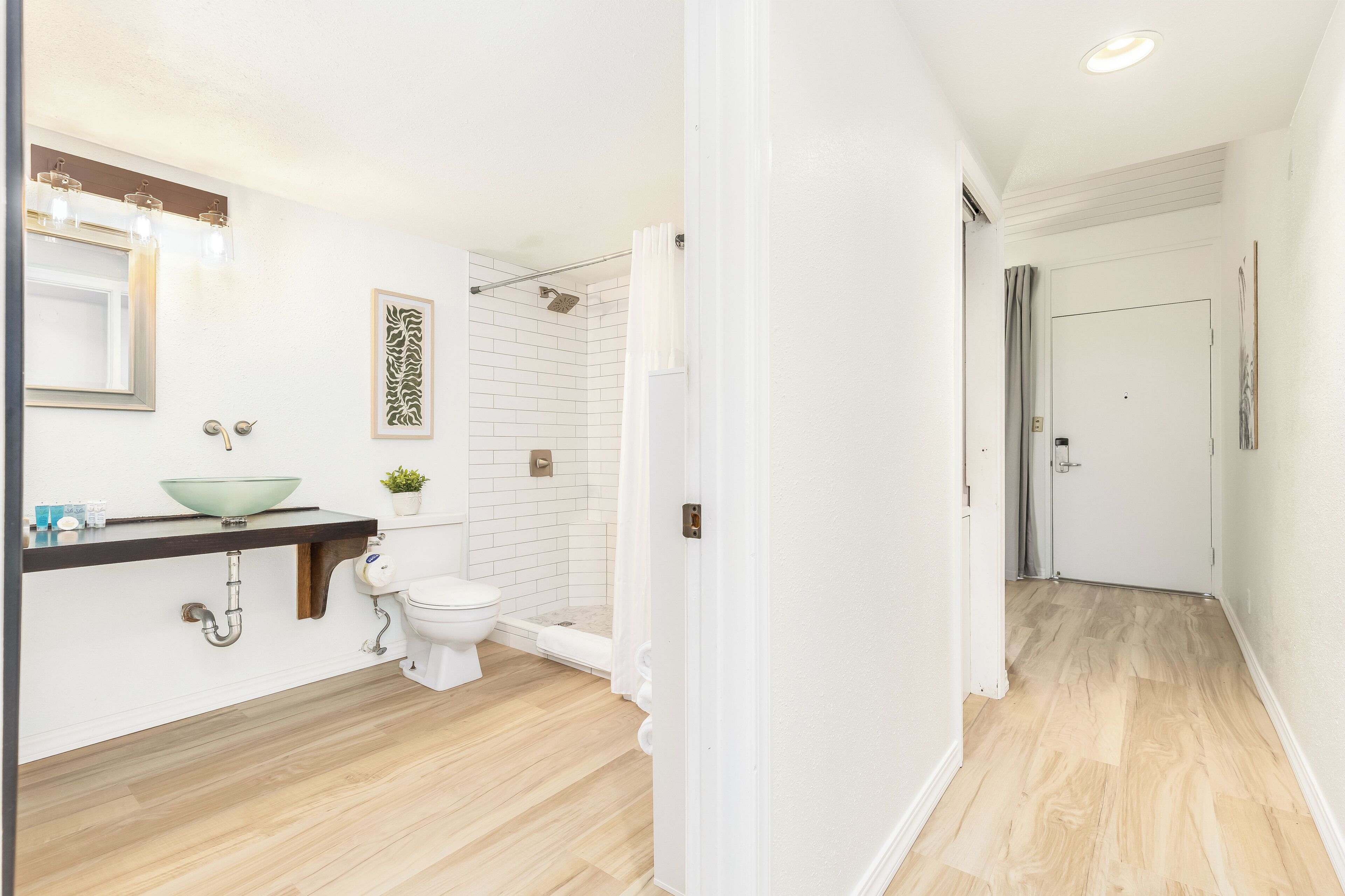 Une salle de bain moderne avec un lavabo, des toilettes et une douche, le tout de couleur blanche.