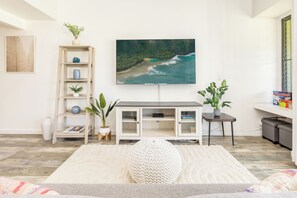Uma sala de estar moderna com televisão de tela plana, estante, mesa lateral e planta em vaso.