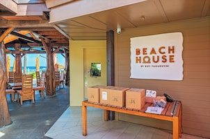 A beach house with wooden furniture and a sign reading "BEACH HOUSE BY ROY YAMAGUCHI".