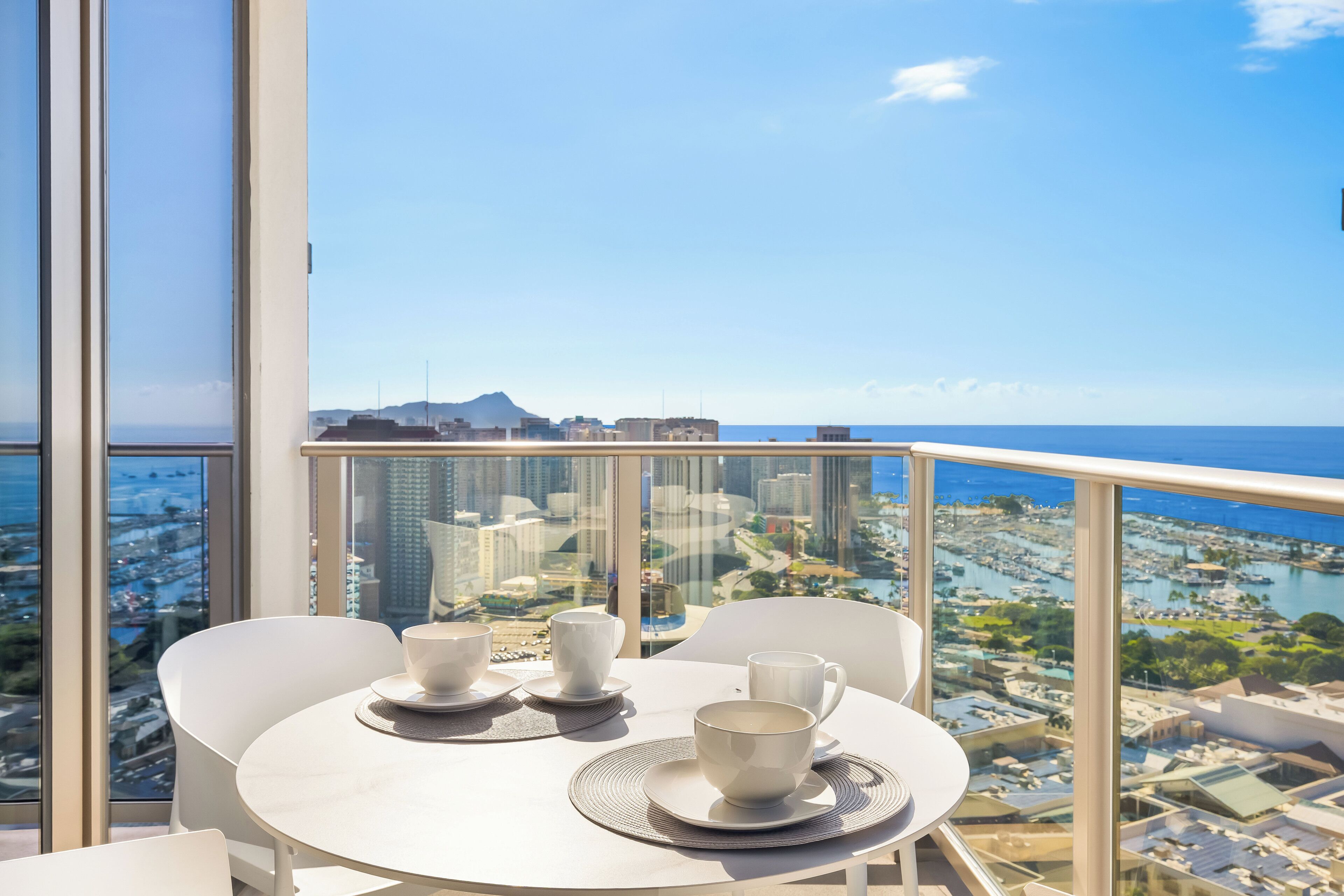 Ein Balkon mit Tisch für zwei Personen, mit Blick auf Stadt und Meer.