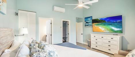 A bedroom with a bed, a ceiling fan, a TV, and a dresser.