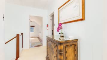 A hallway with a wooden cabinet, a framed picture, and a fire extinguisher.