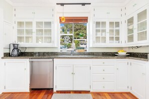 A kitchen with white cabinets, a granite countertop, and a dishwasher.